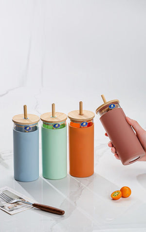 Set of colorful tumblers with wooden lids on a marble surface.
